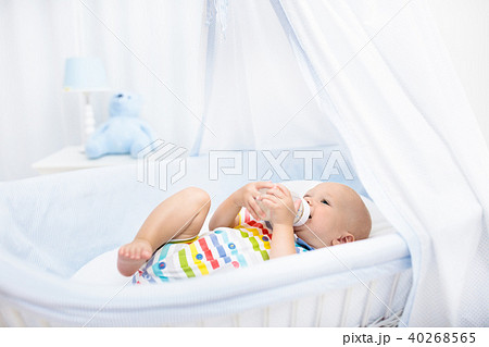 Baby drinking milk. Boy with formula bottle in bed Baby drinking milk. Boy with formula bottle in bed 40268565