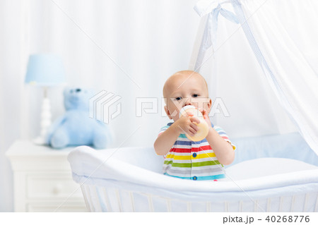 Baby drinking milk. Boy with formula bottle in bed Baby drinking milk. Boy with formula bottle in bed 40268776