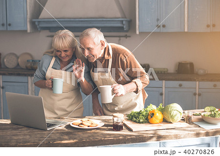 Cheerful senior pensioners enjoying online communication in kitchen Cheerful senior pensioners enjoying online communication in kitchen 40270826