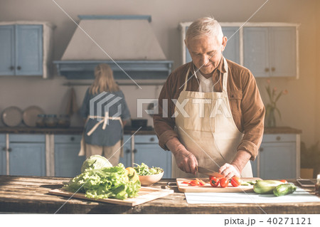 Happy senior man cutting vegetables near woman in kitchen 40271121