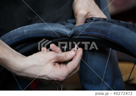 Picture of man repairing wheel of bicycle. 40272972