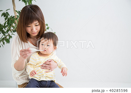 赤ちゃんの熱を測る女性の写真素材