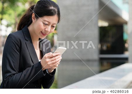 Business woman watches news via mobile phone Business woman watches news via mobile phone 40286016