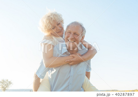 Happy senior man laughing while carrying his partner on his back Happy senior man laughing while carrying his partner on his back 40287897