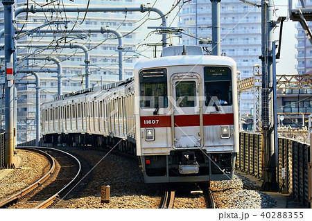 タワーの麓の下町を快走する通勤型ステンレス車 40288355