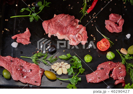 Flat lay of raw beefsteak with vegetables, herbs and spicies on metal tray, close-up, selective 40290427