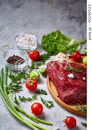 Still life of raw beef meat with vegetables on wooden plate over vintage background, top view 40290523