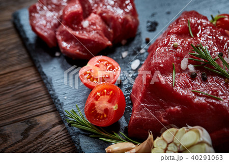 Composition of raw beefsteak on slate board with vegetables and seasoning, selective focus, close-up 40291063