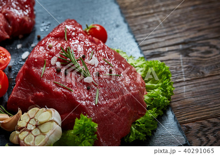 Composition of raw beefsteak on slate board with vegetables and seasoning, selective focus, close-up 40291065