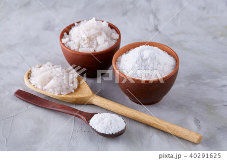 Conceptual composition of salt and pepper on spoons and bowls over light background, top view, close 40291625