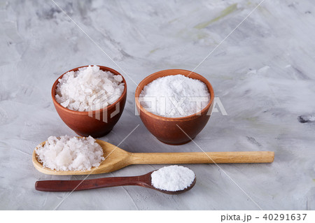 Conceptual composition of salt and pepper on spoons and bowls over light background, top view, close 40291637