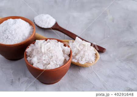 Conceptual composition of salt and pepper on spoons and bowls over light background, top view, close 40291648