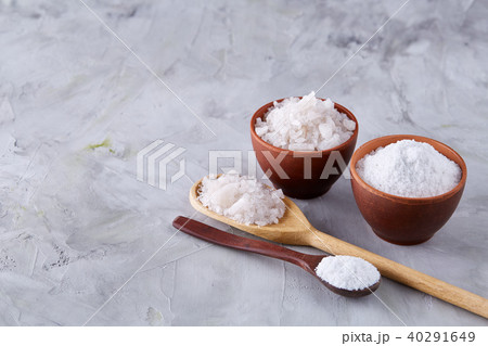 Conceptual composition of salt and pepper on spoons and bowls over light background, top view, close 40291649