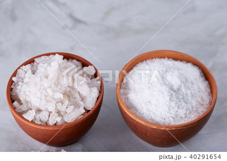 Conceptual composition of salt and pepper on spoons and bowls over light background, top view, close 40291654