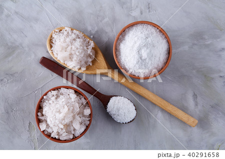 Conceptual composition of salt and pepper on spoons and bowls over light background, top view, close 40291658