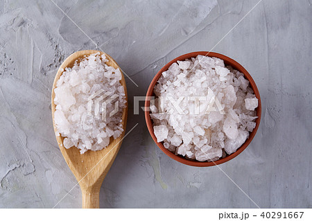 Conceptual composition of salt and pepper on spoons and bowls over light background, top view, close 40291667