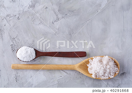 Conceptual composition of salt and pepper on spoons and bowls over light background, top view, close 40291668