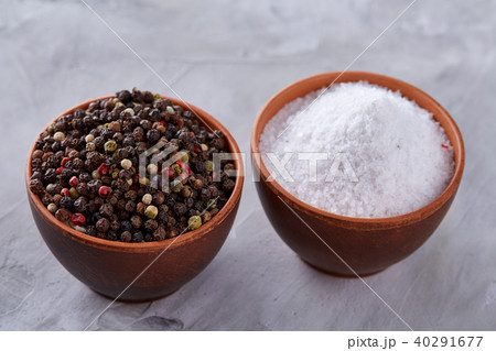 Conceptual composition of salt and pepper on spoons and bowls over light background, top view, close 40291677