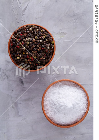 Conceptual composition of salt and pepper on spoons and bowls over light background, top view, close 40291690