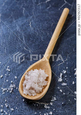 Crystal sea salt in a wooden spoon on dark background, top view, close-up, selective focus. Crystal sea salt in a wooden spoon on dark background, top view, close-up, selective focus. 40292317