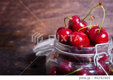 Big red cherries in a glass jar on dark wooden 40292800