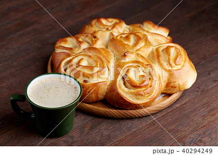 Creamy coffee in cup with homemade rose bread on vintage wooden background, close-up, selective 40294249