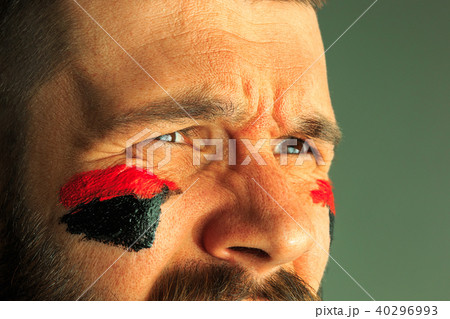 Portrait of a man with the flag of the Germany painted on him face. 40296993