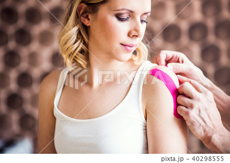 Senior male physiotherapist applying tape on a female patient. Close up. Senior male physiotherapist applying tape on a female patient. Close up. 40298555