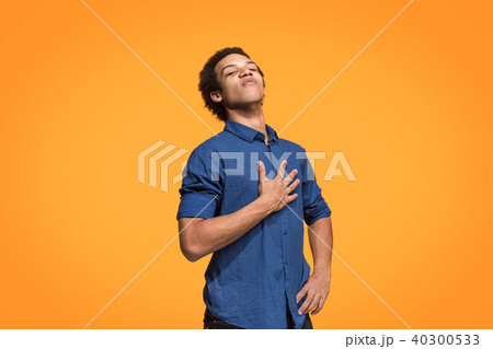 Beautiful male half-length portrait isolated on orange studio backgroud. The young emotional 40300533