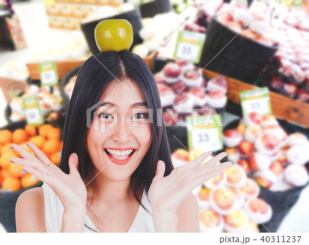 Beautiful woman holding apple on supermarket blur Beautiful woman holding apple on supermarket blur 40311237