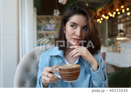 Beautiful young woman sitting in a cafe and drinking coffee. Beautiful young woman sitting in a cafe and drinking coffee. 40315030