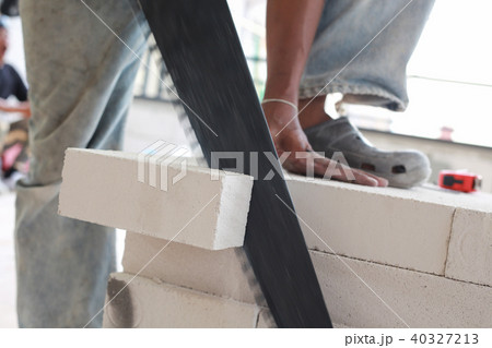 Worker cutting bricks with crosscut saw. Worker cutting bricks with crosscut saw. 40327213