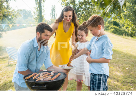 Dedicated father helping son to use wooden tongs during family picnic Dedicated father helping son to use wooden tongs during family picnic 40328774