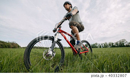 Man riding bicycle on a meadow with green grass 40332807