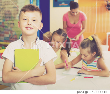 Cheerful boy pupil standing in elementary school class Cheerful boy pupil standing in elementary school class 40334316