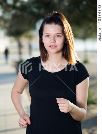 Adult female in black T-shirt is jogging 40334348
