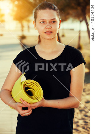 Girl in black T-shirt with carpet in her hands is preparing for 40334434