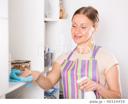 Positive woman wiping shelves 40334459