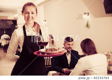 Affable female waiter is standing with order in luxury restaurante Affable female waiter is standing with order in luxury restaurante 40334764