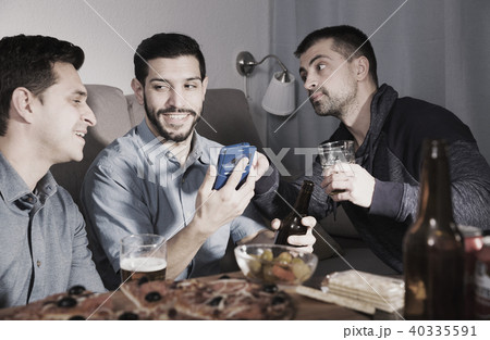 Happy males talking over beer with pizza at home Happy males talking over beer with pizza at home 40335591