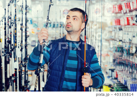 Man shopper choosing ocean fishing rod in hop Man shopper choosing ocean fishing rod in hop 40335814