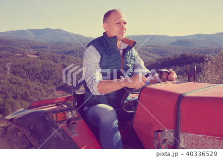 Confident male owner of vineyard driving tractor outdoors in sunny day Confident male owner of vineyard driving tractor outdoors in sunny day 40336529