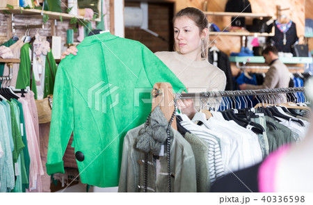 Smiling woman is choosing clothes and looking on green pullover 40336598