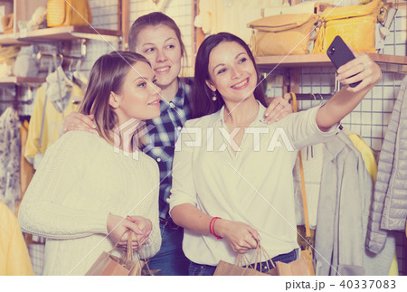Women friends making selfie in clothes shop, carrying paper bags Women friends making selfie in clothes shop, carrying paper bags 40337083