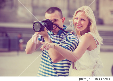 Two cheerful tourists holding camera in hands Two cheerful tourists holding camera in hands 40337263