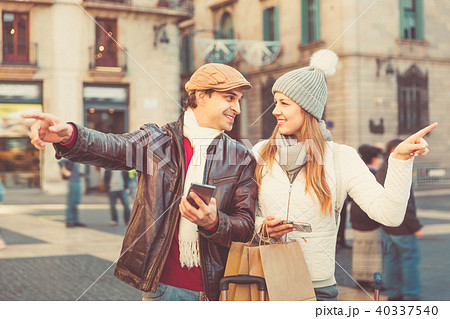 Couple at the historical city center with mobile phones pointing finger Couple at the historical city center with mobile phones pointing finger 40337540