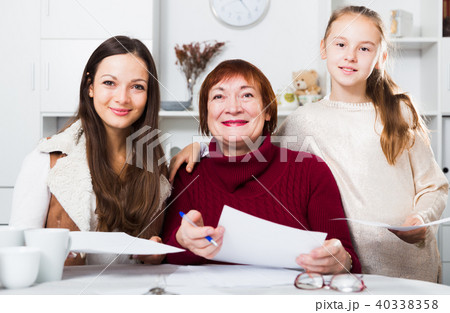 Smiling senior woman with family writing papers 40338358