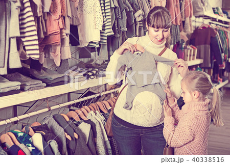 Pregnant mother and daughter choosing romper suit for baby in children’s clothes shop Pregnant mother and daughter choosing romper suit for baby in children’s clothes shop 40338516