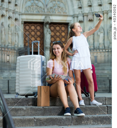 Small girl making selfie with phone, traveling with mother Small girl making selfie with phone, traveling with mother 40340092