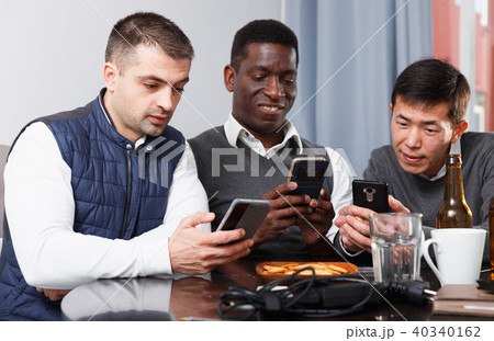 Three friends are chatting each in his phone while relaxing together 40340162